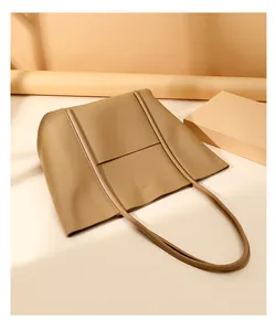 Detailed view of warm khaki leather tote bag featuring stitching and slim shoulder strap