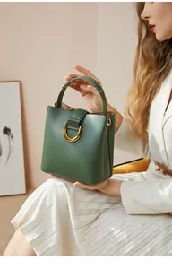 Détail du sac seau vert foncé avec boucle dorée en D et texture cuir de haute qualité