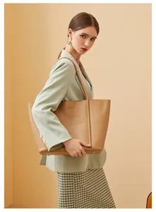 Side view detail of khaki leather tote bag showing fine stitching and metal bottom studs
