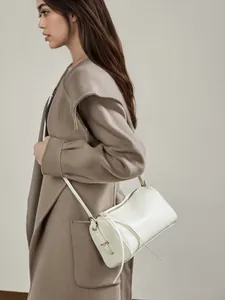 Sac bandoulière en cuir ivoire porté avec un manteau en cachemire de luxe beige