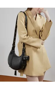 Detail of black croc-embossed crescent bag with wide strap and micro pouch on model