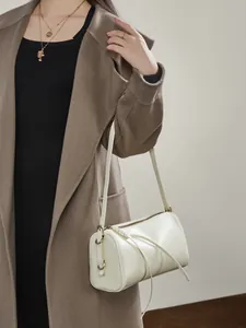 Sac cylindre élégant en cuir crème avec détails dorés et fermeture éclair à pampille longue