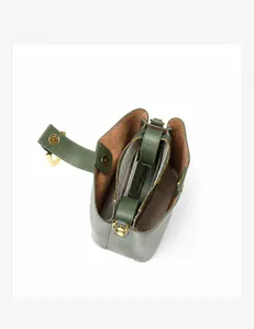 Détail d'un sac seau en cuir vert foncé avec compartiments internes et garniture dorée