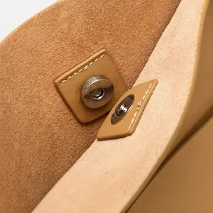 Detail of magnetic zinc alloy clasp and premium leather texture on a light brown tote bag