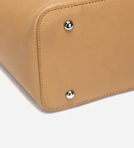 Detail of leather tote bag bottom with silver protective metal studs and stitching