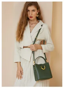 Détail du sac seau vert foncé avec ferrures dorées et bandoulière amovible élégante