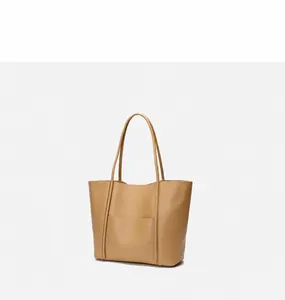 Detailed side view of tan leather tote bag showing structural seams and flat handle