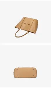 Close-up of khaki leather tote bag bottom featuring four silver protective metal studs
