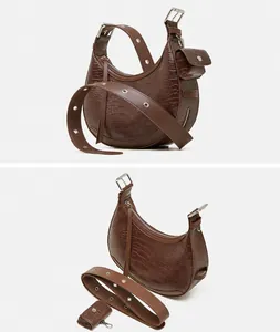 Detail view of brown crocodile texture crescent bag showing side profile and silver hardware