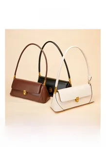 Minimalist leather baguette bags in brown, black, and cream with gold metal buckles