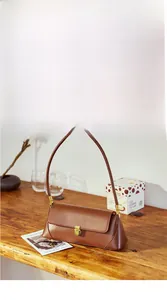 Detailed close-up of a caramel brown leather baguette bag on a wooden table setup