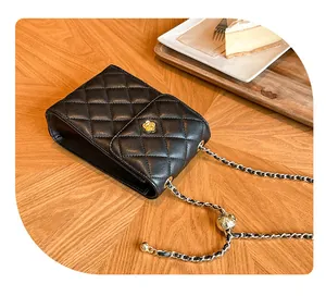 Detail einer schwarzen gesteppten Mini-Tasche mit Goldblumenschnalle und verstellbarer Kette