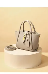 Detail of cream leather bucket bag showing textured finish and golden turn-lock hardware