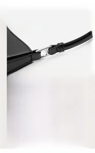 Detailed close-up of the polished silver H-shaped connector on a black leather handbag