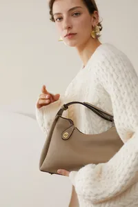 Détail d'un sac à main en cuir grainé avec fermoir rotatif doré et fermeture éclair chic