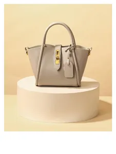 Detail of beige pebbled leather bucket bag with gold metal twist lock on a display stand
