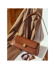 Detailed macro view of the brown leather baguette bag with a premium golden metal clasp