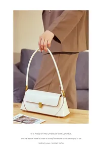 Detailed close-up of a white leather baguette bag with a gold buckle and fine grain texture