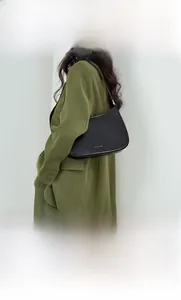 Close-up of black leather hobo bag worn by model with adjustable shoulder strap detail