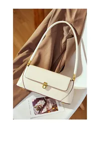 Detail of genuine leather baguette bag with golden metal clasp and premium edge oil finishing