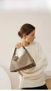 Vue détaillée du sac en cuir kaki avec texture grainée et pieds en métal doré sur le fond
