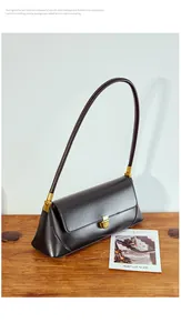 Close-up of black leather baguette bag with elegant gold buckle and side pleats