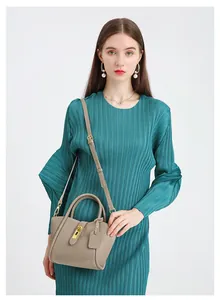 Close-up of litchi grain leather bucket bag in khaki worn with a pleated green dress