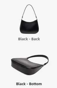 Detail view of the back and bottom of a black leather baguette bag with gold logo