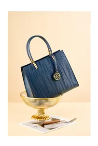 Detail of dark blue wave pattern leather handbag with gold floral logo and handle