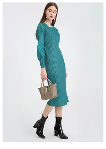 Detail view of water blue pleated dress paired with a stylish light brown bucket bag