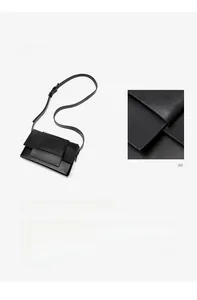 Detail of black matte leather crossbody bag featuring a large square buckle and long strap