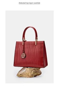 Detail view of red top layer cowhide handbag featuring wave texture and gold hardware