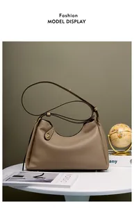 Détail du sac hobo en cuir grainé marron avec accessoires dorés sur fond vert foncé