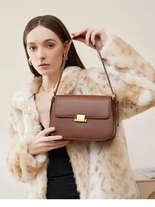 Close-up of brown matte leather bag with gold buckle on model in spotted fur coat