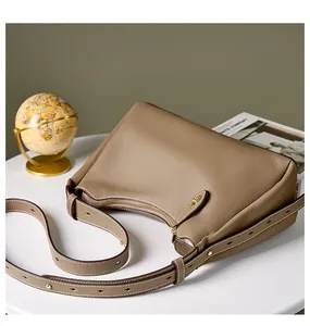 Détail du sac demi-lune en cuir grainé avec bandoulière réglable et zip doré chic