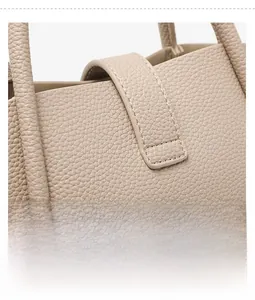 Close-up of litchi grain leather texture and precise stitching on beige bucket bag
