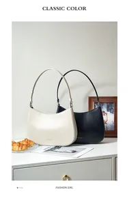 Detail view of black and beige leather hobo bags with adjustable straps on a white cabinet