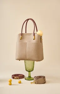 Dettaglio borsa a secchiello in pelle beige con tracolla in pelle e fascia etnica