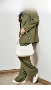 Minimalist white leather half-moon baguette bag shown worn by a model in a green suit