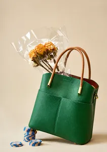 Dettaglio della borsa a secchiello in pelle verde scuro con manico circolare marrone