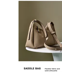 Détail macro du sac selle en cuir kaki avec garnitures dorées et finition texturée