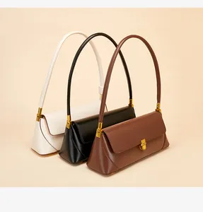 Close-up of three minimalist leather baguette bags in white, black, and brown with gold buckles