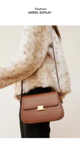 Close-up of a vintage brown leather crossbody bag with a gold buckle on a model