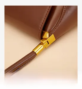 Macro shot of brown leather texture and bronze hardware on the French baguette bag