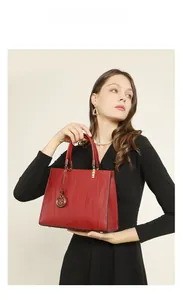 Close-up of red leather handbag with textured wave pattern and gold metal pendant detail