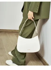 Close-up of white leather hobo bag with gold Fashion & Trend text on a green suit background