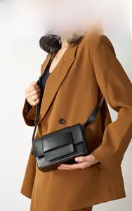 Detailed close-up of woven texture and fold closure on a black leather crossbody bag