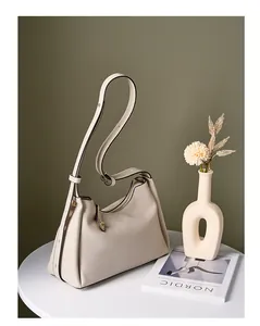 Détail du sac hobo en cuir grainé beige avec garniture dorée sur une table blanche