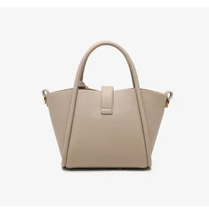 Close-up of beige lychee grain leather texture and handle stitching on bucket bag