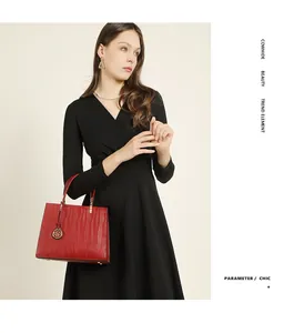 Close-up of red cowhide handbag with wave texture and gold hardware held by a model